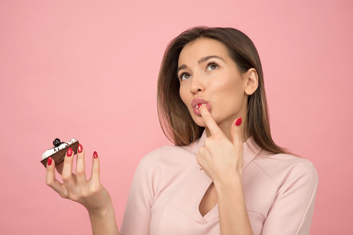 woman-eating-cupcake-while-standing-near-pink-background-1036621 woman-eating-cupcake-while-standing-near-pink-background-1036621